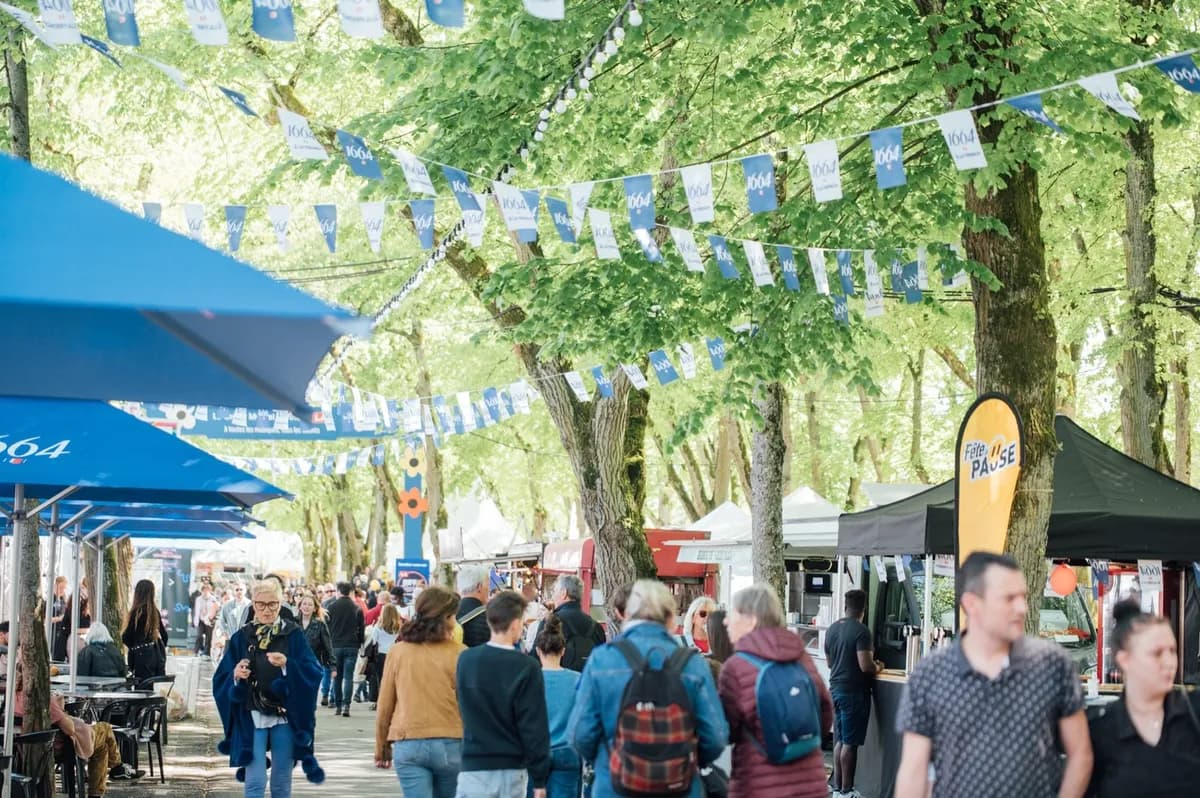 Festival crowds roam Bourges streets at Le Printemps de Bourges 2026, grabbing bites at free stalls and bars between open air stages. Paid indoor gigs mix with casual daytime vibes for all.