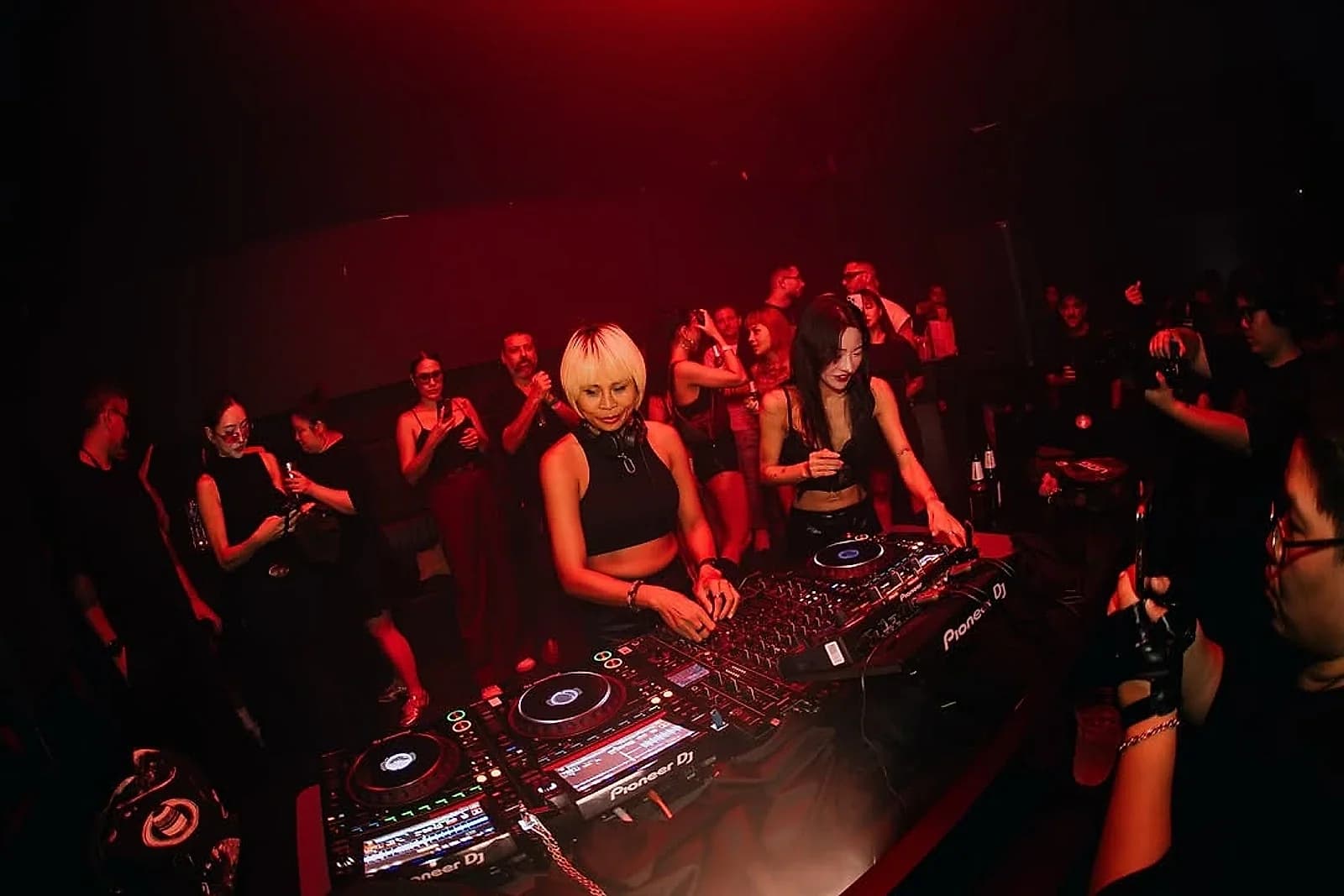 Back to back at the booth, late into a Bangkok club night.