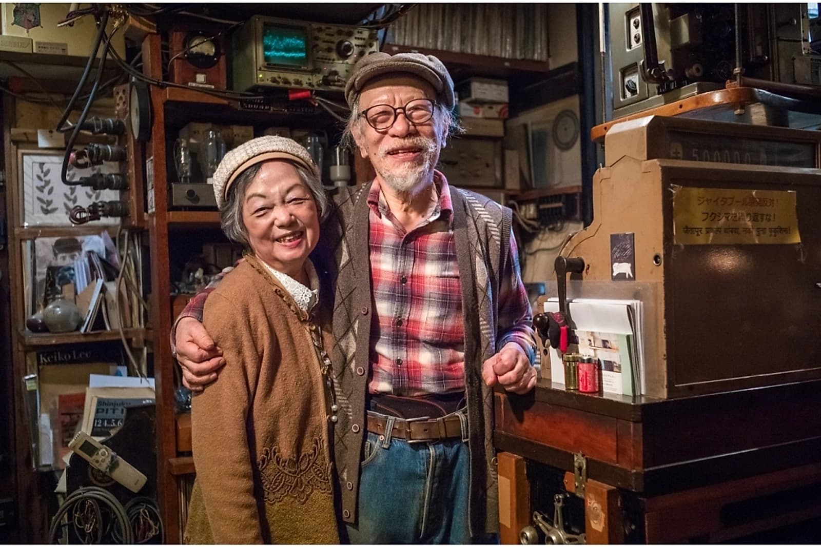 An ongaku kissa owner and his wife inside their shop, stacked floor to ceiling with decades of vintage audio equipment.