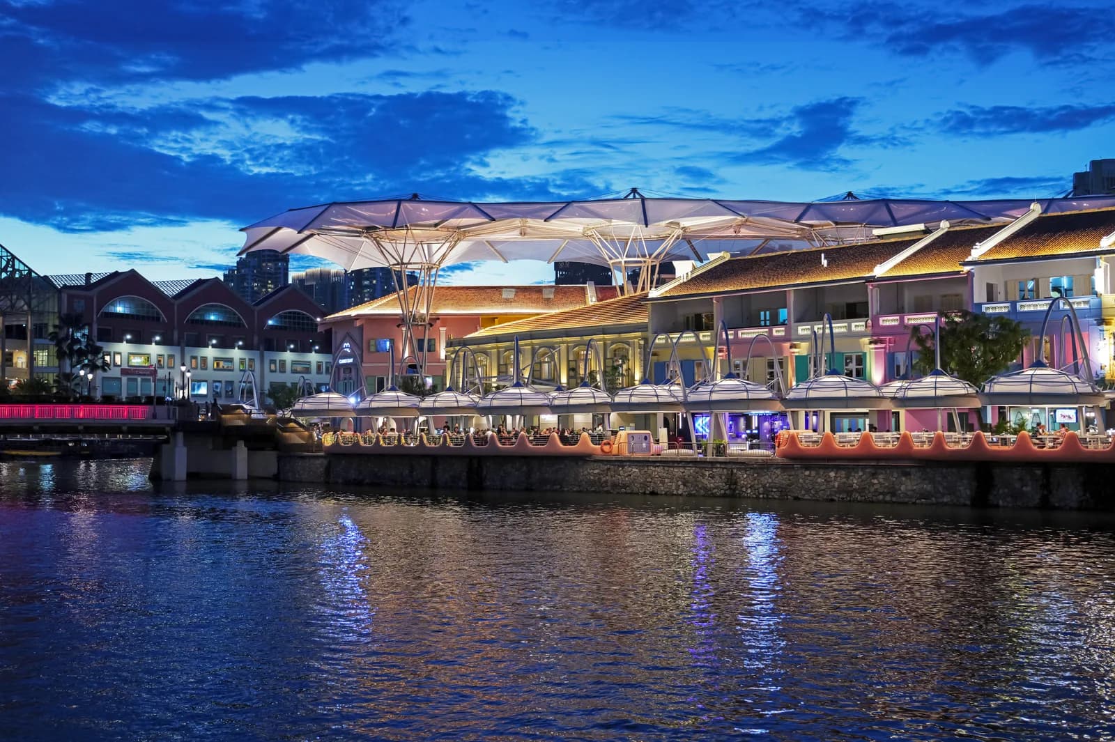 Clarke Quay's canopy-covered riverfront strip at dusk, before the crowds move in.
